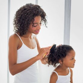 mom brushing daughters hair before head lice treatment